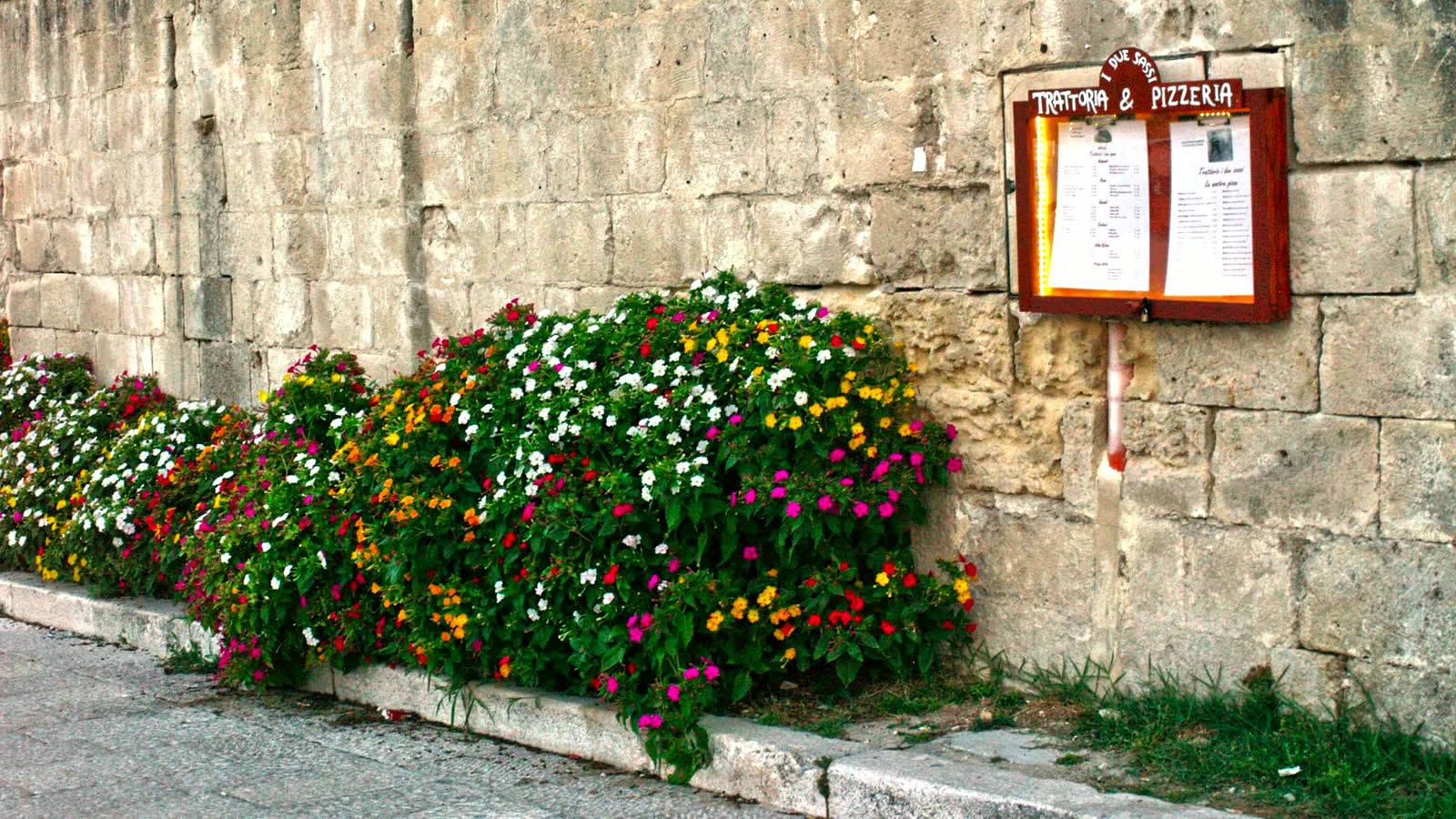 Il muro fiorito lungo la via, col menù esposto in bacheca