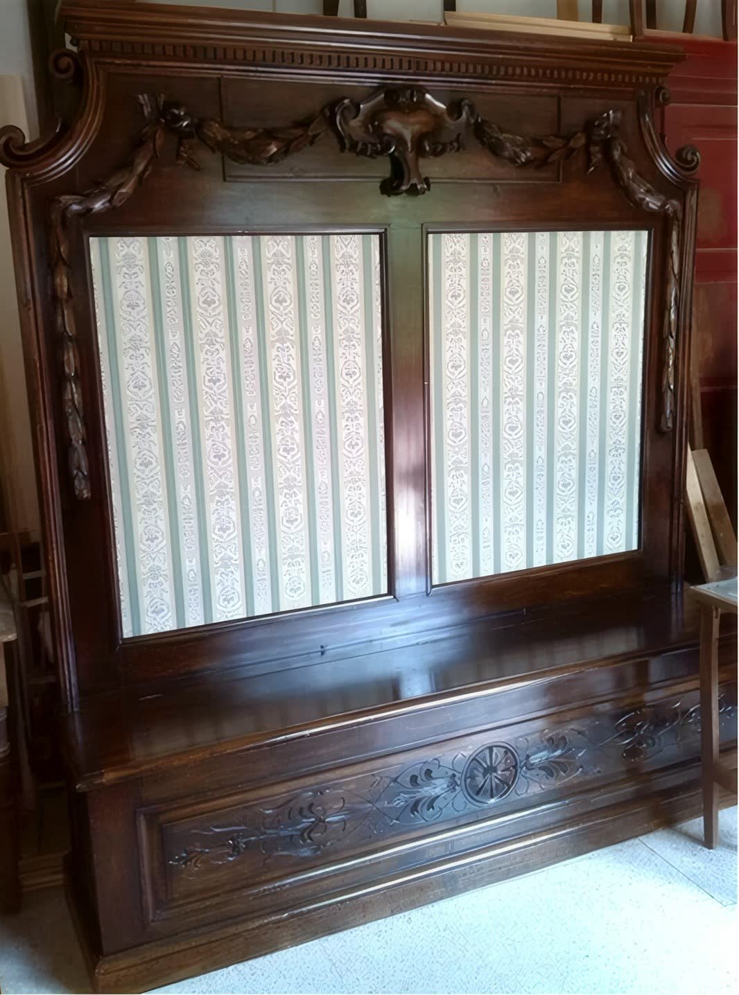 La stessa panca a specchiera dopo il restauro, con il legno lucidato e le tappezzerie rifatte